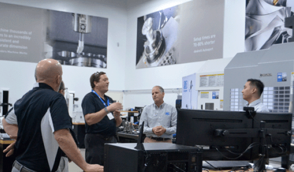 Men talking next to a CNC machine during distributor training.